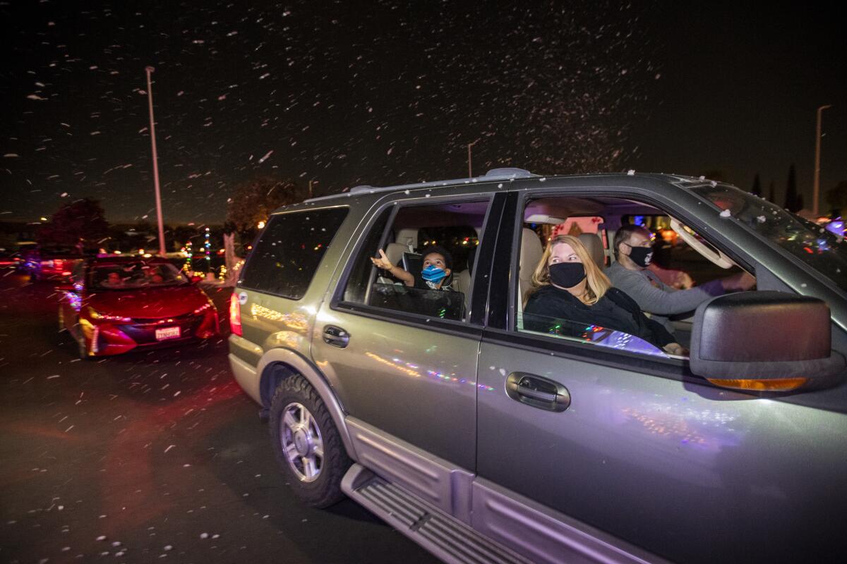 Locals drive through falling snow during a holiday toy drive featuring the Snoopy House exhibit at IKEA in Costa Mesa.