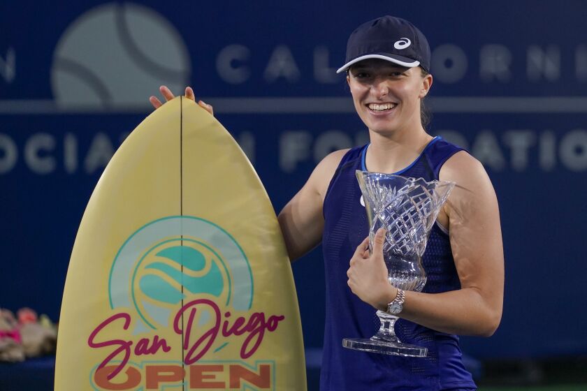 Iga Swiatek, of Poland, holds the trophy and surfboard after defeating Donna Vekic, of Croatia, to win the San Diego Open tennis tournament, Sunday, Oct. 16, 2022, in San Diego. (AP Photo/Gregory Bull)