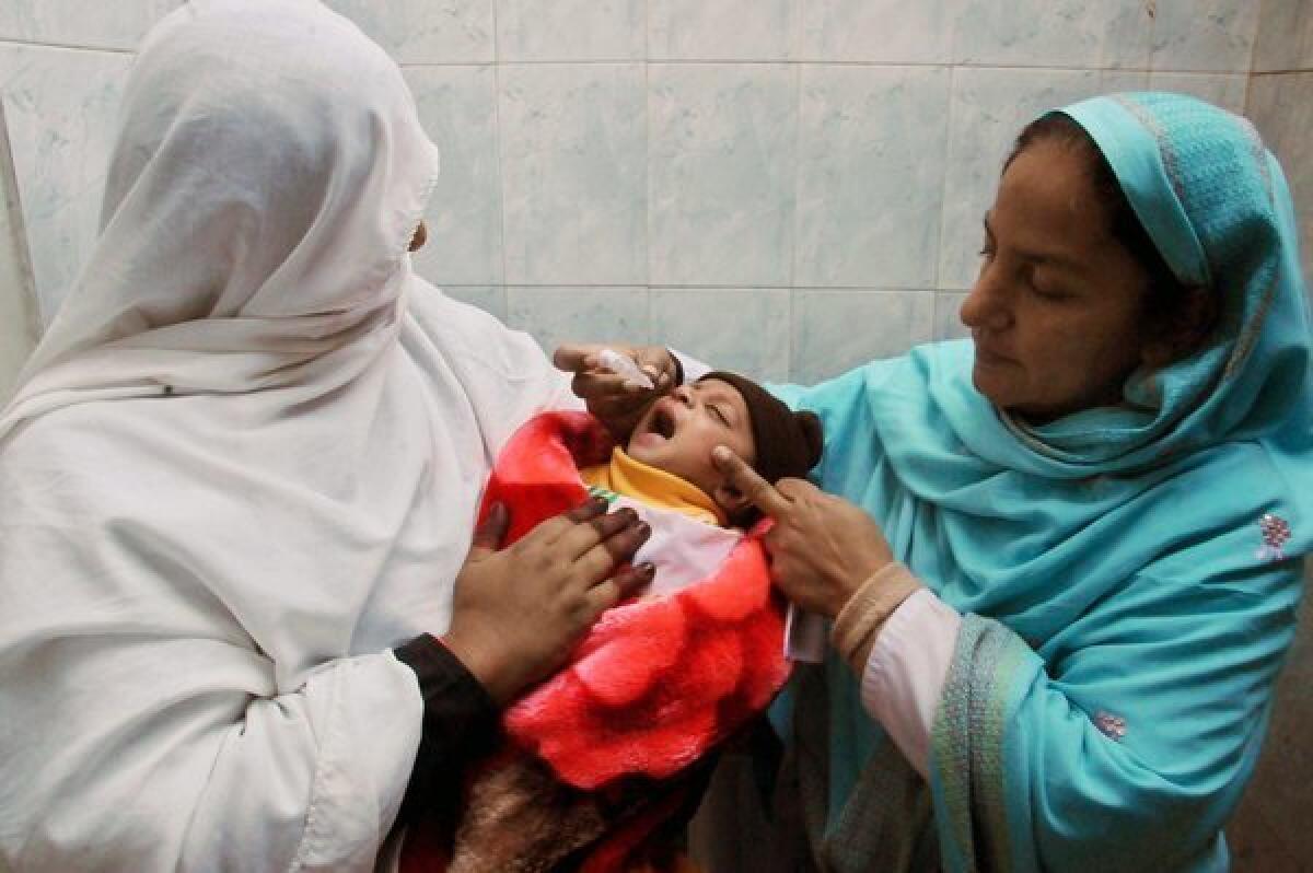 Health workers in Peshawar, Pakistan, give a polio vaccine to a child during a three-day nationwide vaccination campaign.