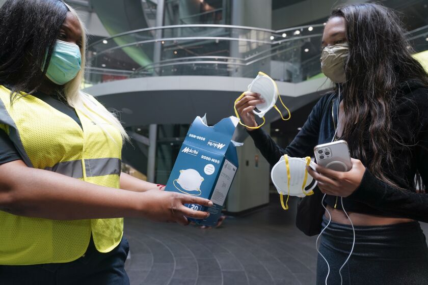 MTA employee Shanita Hancle, left, hands out masks to commuters at the entrance to a subway station in New York, Thursday, June 8, 2023. Air pollution from Canadian wildfires are cloaking the northeastern U.S. for a second day. (AP Photo/Seth Wenig)