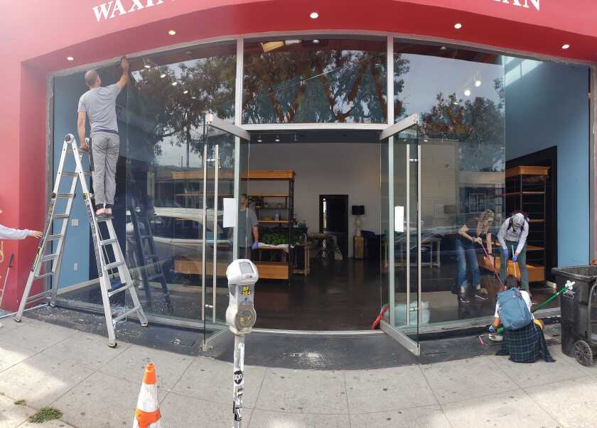Friends and workers board up the vandalized Melrose Avenue business Wax.