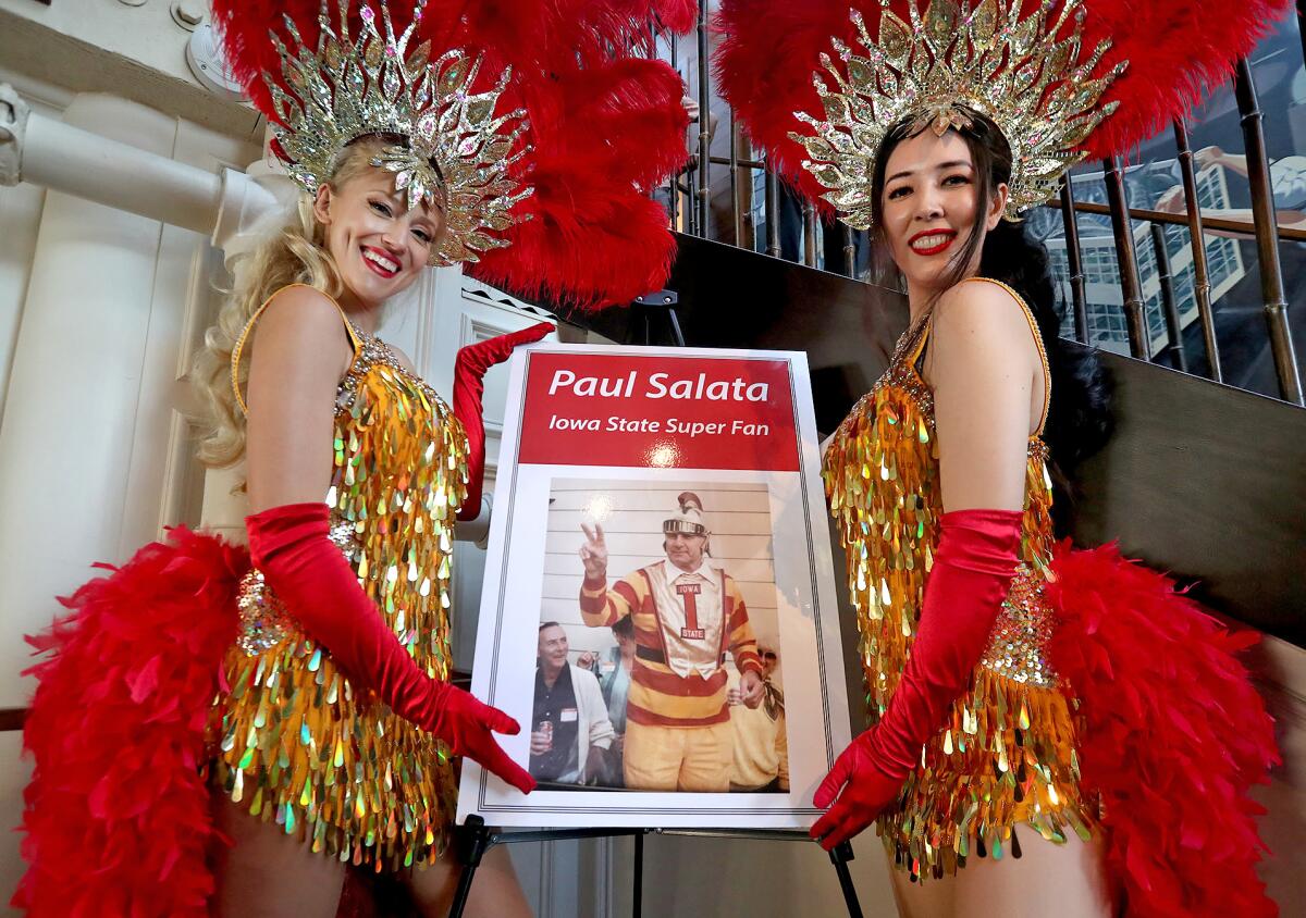 Two showgirls in the spirit of the San Francisco 49ers flank a picture of Paul Salata, founder of Irrelevant Week.