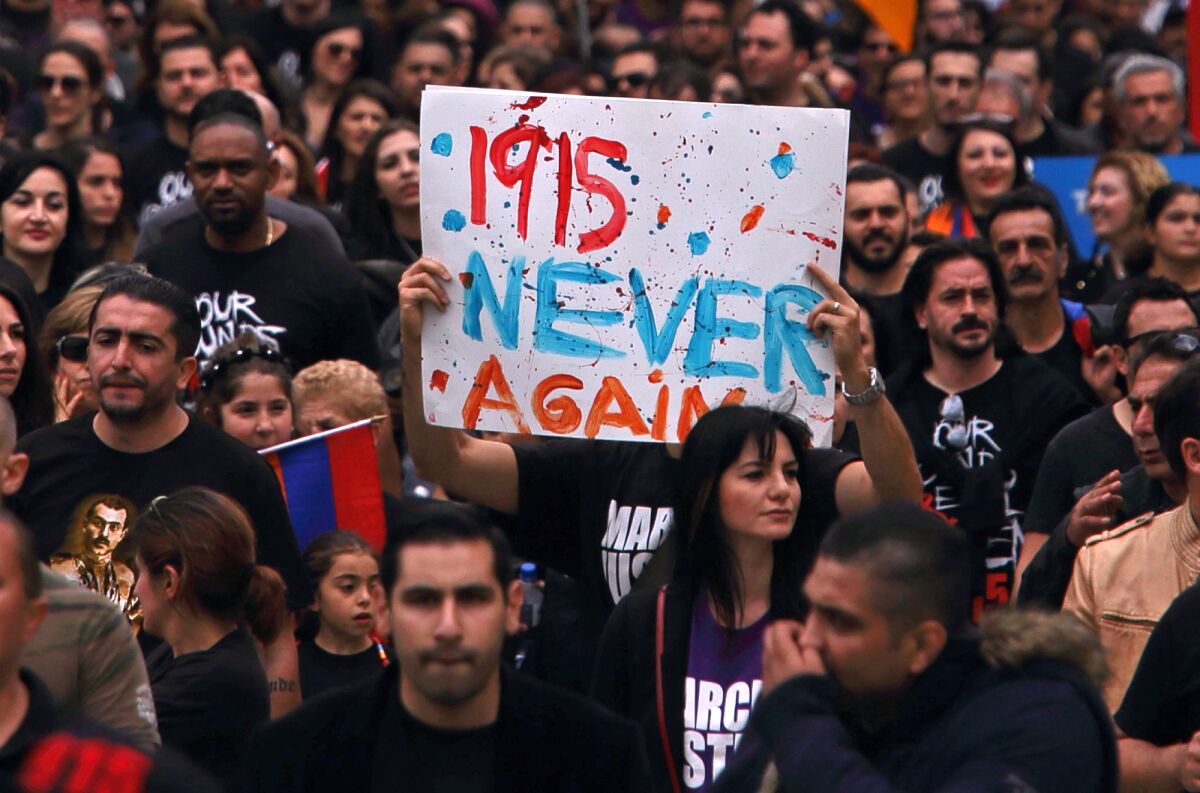 A protester holds a sign that says "1915 never again."