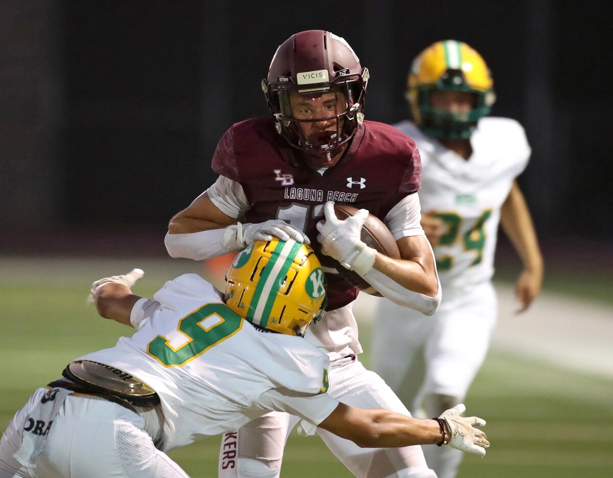 Luke Jolley of Laguna Beach (13) tries to fend off a tackler during Friday night's game against Kennedy.