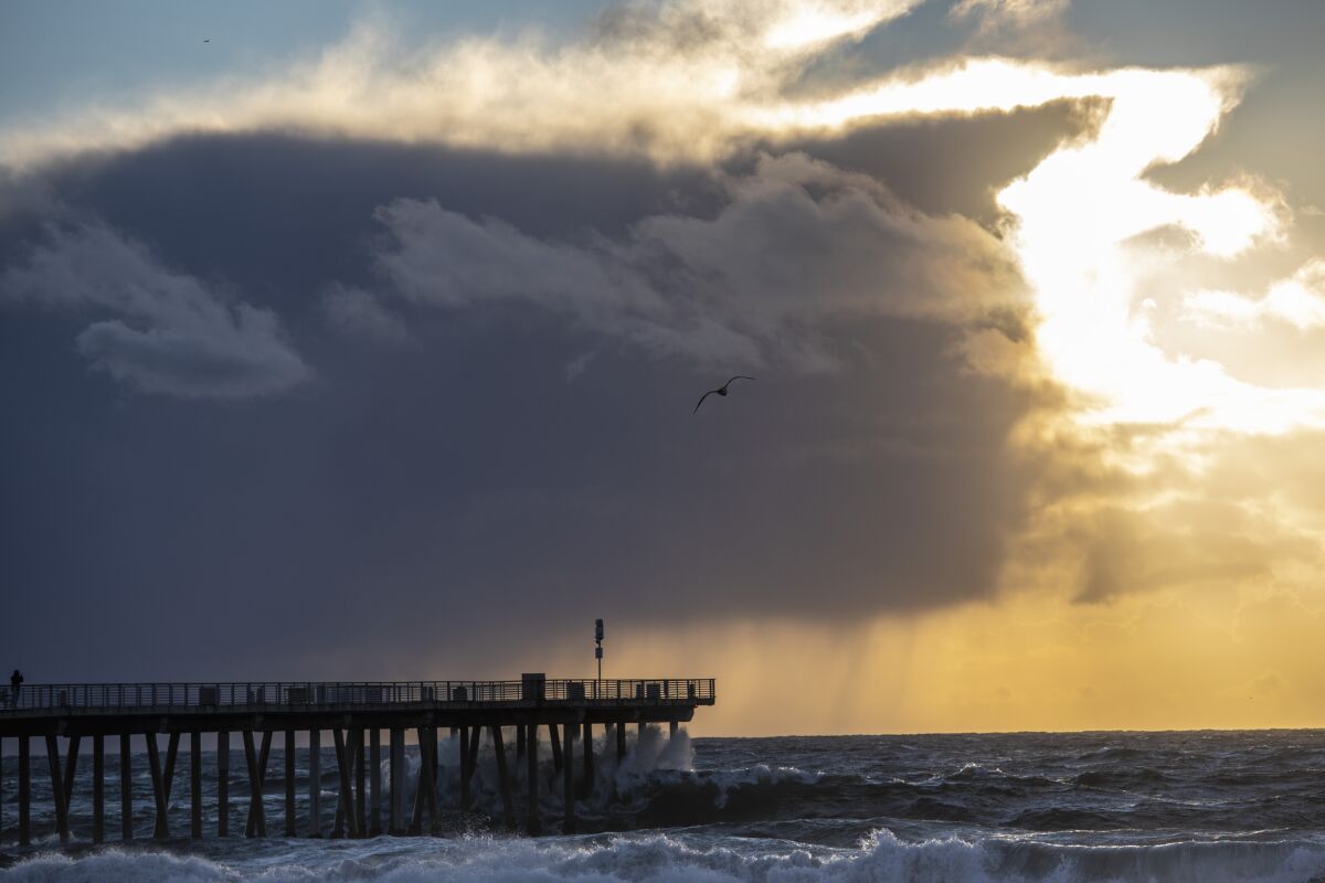 High surf hits the Hermosa Beach Pier as a winter storm and dark clouds move through.