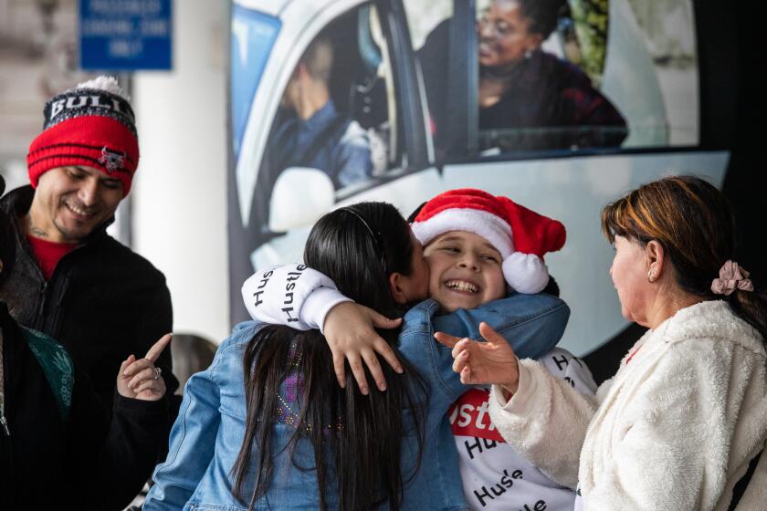 Los Angeles, CA - December 22: Holiday traveler Michael Bisenieks, 11, center, embraces relatives as he arrives at LAX on Thursday, Dec. 22, 2022 in Los Angeles, CA. (Brian van der Brug / Los Angeles Times)