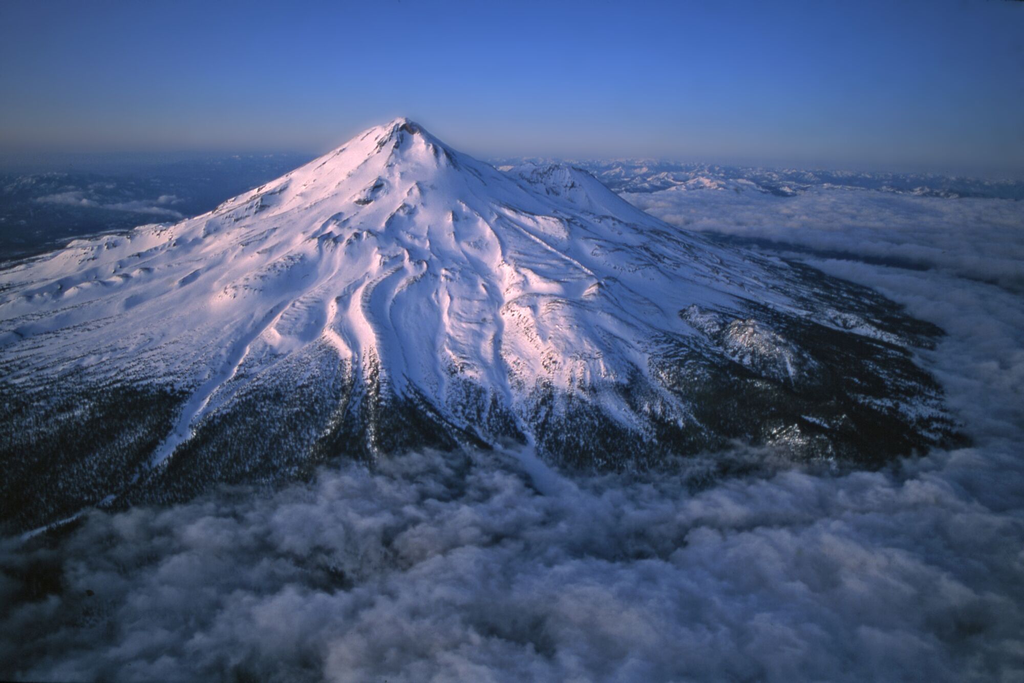 A snow-covered, conical mountain peak