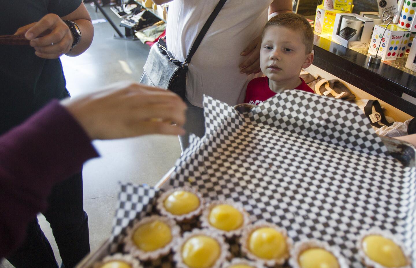 Cash Peoples, 4, eyes a lemon curd tart sample at the Blackmarket Bakery during an open house to celebrate the one-year anniversary of the bakery being open at The Camp in on Saturday, January 25. (Scott Smeltzer, Daily Pilot)