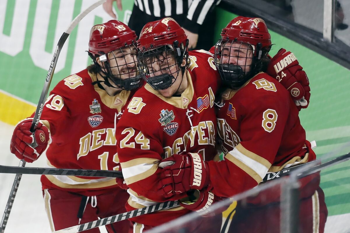 Denver's Carter Savoie (8) celebrates his winning goal with Bobby Brink (24) and Cole Guttman (19) in overtime during an NCAA men's Frozen Four semifinal hockey game against Michigan, Thursday, April 7, 2022, in Boston. (AP Photo/Michael Dwyer)