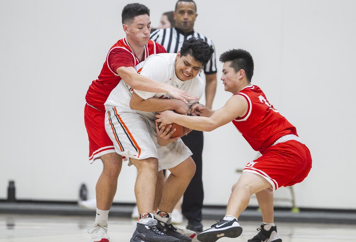 Los Amigos' Christopher Gonzalez, center, fights for a ball with Loara's Logan Beyler, left, and Nick Nguyen during a Garden Grove League game on Tuesday.