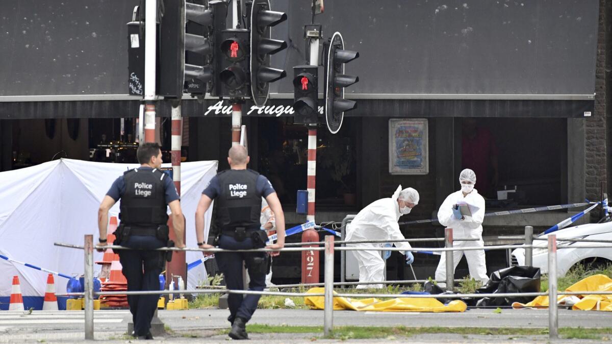 Forensic police, right, investigate at the scene of a shooting in Liege, Belgium, after a gunman killed three people, including two police officers, on Tuesday.