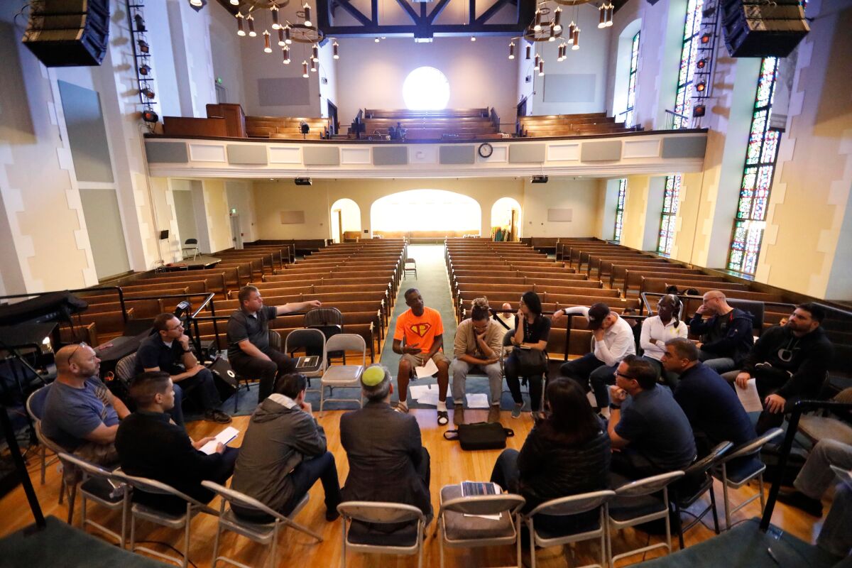 People sit in chairs in a circle inside a church.