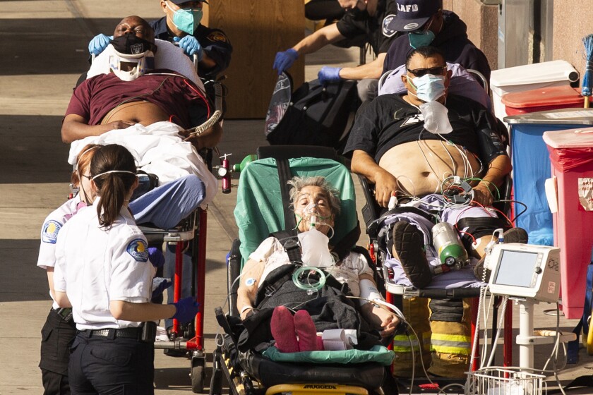 Pacientes esperan fuera de la sala de emergencias mientras son llevados por una ambulancia