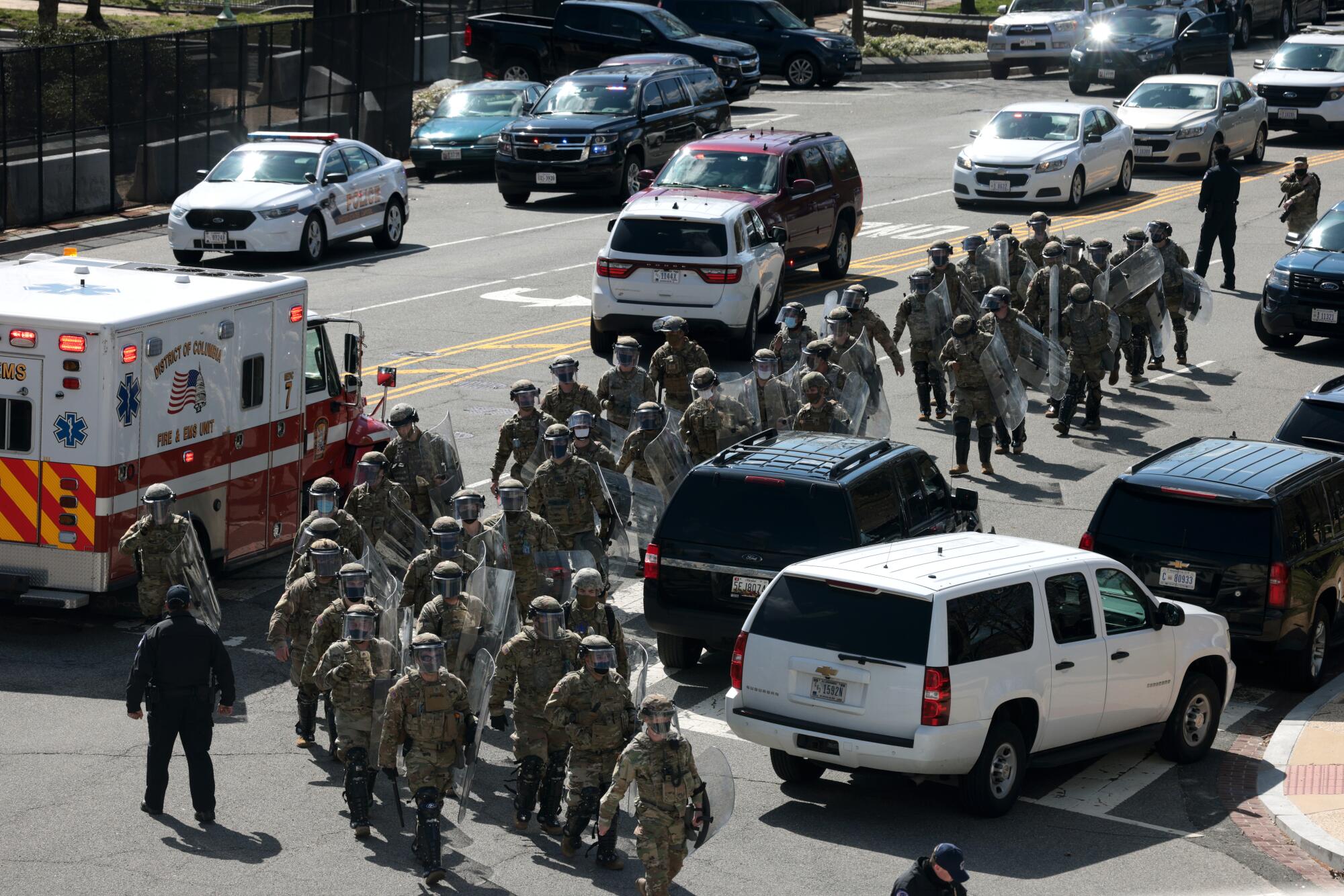 National Guard troops carrying riot shields walk up Constitution Ave. after a vehicle charged a barricade at the U.S. Capitol