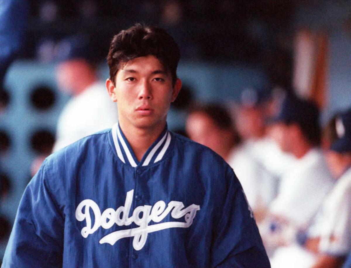 Hideo Nomo, wearing a Dodgers jacket, walks in the dugout during a 1995 game.