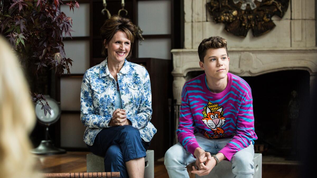 A woman in a blue floral print jacket sits next to her son