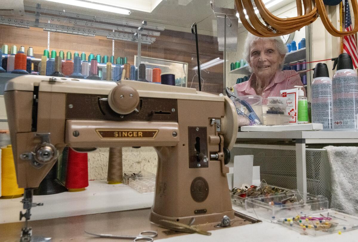Barbara "Corki" Rawlings peers over her workbench and favorite sewing machine Tuesday at her Newport Beach shop.