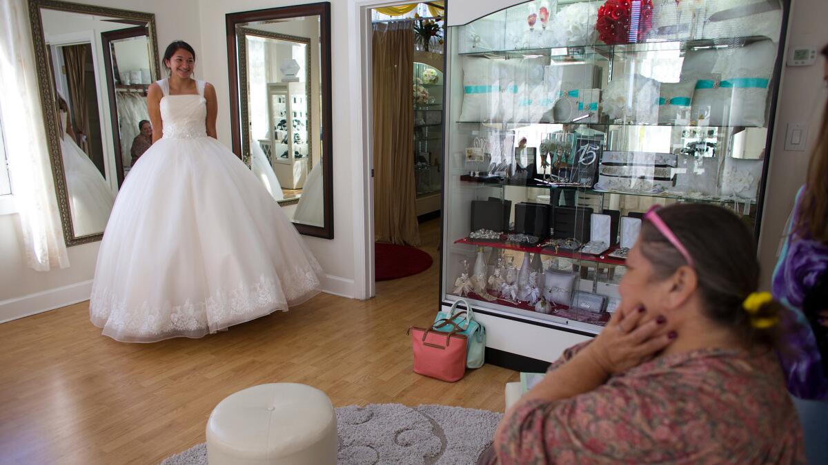 Audrey Arellano, 14, of Irvine shows off a princess-style quinceañera dress at Genesis Bridal Boutique."The newer clientele, the Americans and younger generation Hispanics are more selective. They don't want as many ruffles in their dresses," shop owner Lilia Cerpas says.