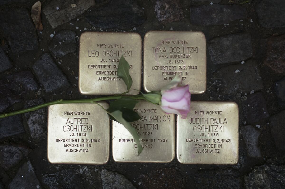 A flower lays on polished so-called 'Stolpersteine' or 'stumbling stones' commemorating people deported and killed by the Nazis in front of a resident building in Berlin, Germany, Tuesday, Nov. 9, 2021, the 83th anniversary of the Nazis' anti-Jewish pogrom in 1938. The stones are among thousands set into sidewalks in front of houses in Germany and other European countries where victims of the Nazis lived or worked before they were deported and killed. The inscriptions include the names of the victims, the dates of their birth and of their deportation and murder. To stones are cleaned by residents on and around the Nov. 9 anniversary. (AP Photo/Markus Schreiber)