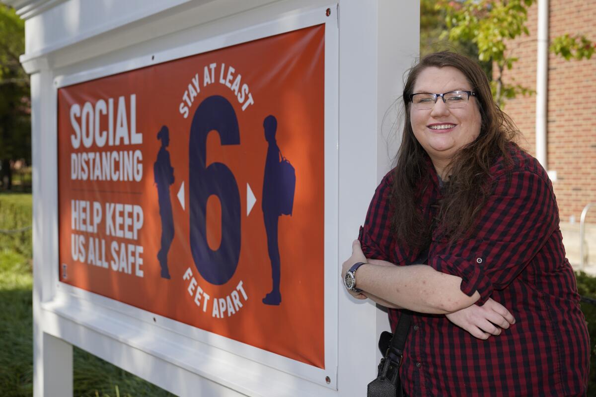 Sarah Keeley stands next to a University of Illinois campus sign that says "Social distancing: Help keep us all safe."
