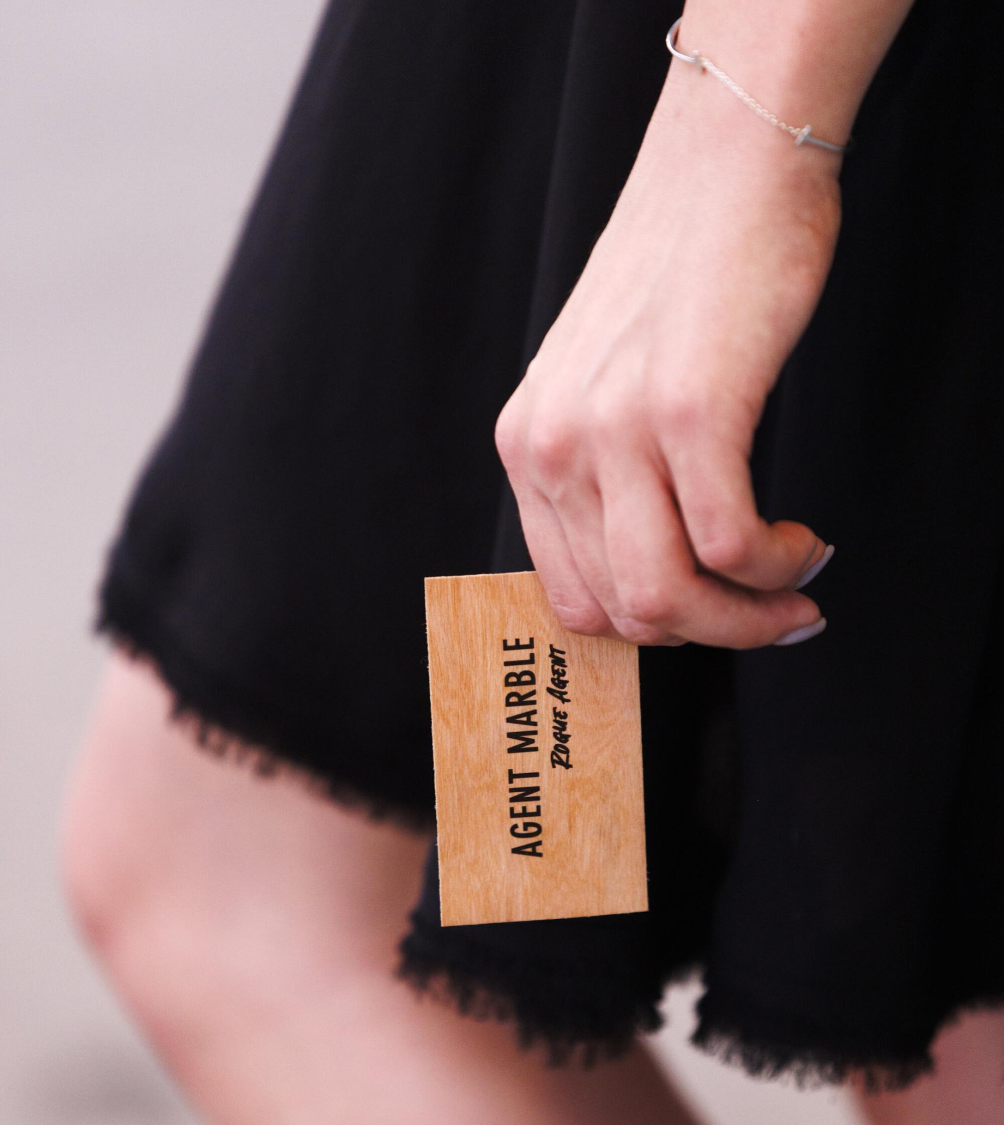 A hand holds a business card printed with the words "Agent Marble" and "Rebel Agent"