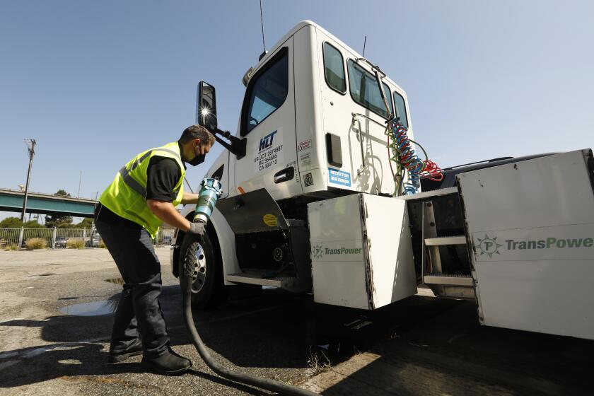 Wilmington, California-July 30, 2021-Total Transportation Services Inc. has an electric truck in its fleet at the Port of Los Angeles.  Ryan Sickles is the heavy haul terminal manager for Total Transportation Services Inc. He connects power to the truck.  (Carolyn Cole / Los Angeles Times)