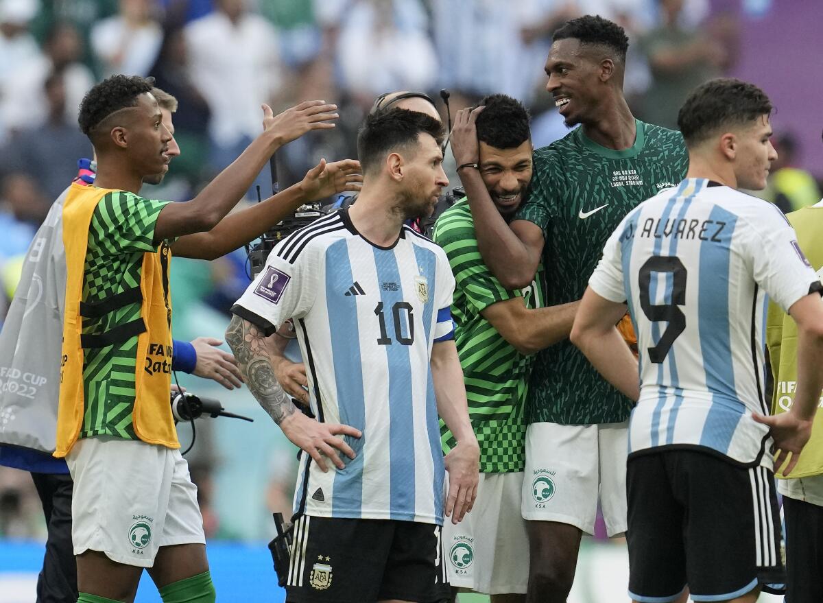 Argentina's Lionel Messi standing beside Saudi Arabia's players celebrating after winning the World Cup group C soccer match