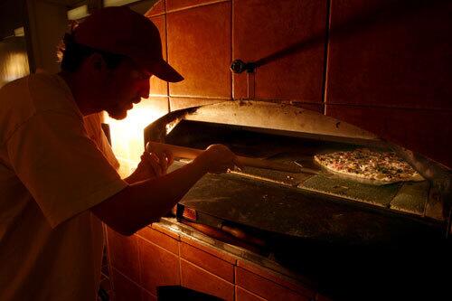 Angelo Vukelja checks one of the Croatian pizzas baking in the brick oven at Pavich's Brick Oven Pizzeria in San Pedro.