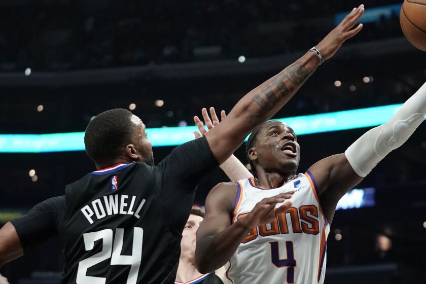 Phoenix Suns guard Aaron Holiday, right, shoots as Los Angeles Clippers forward Norman Powell defends 