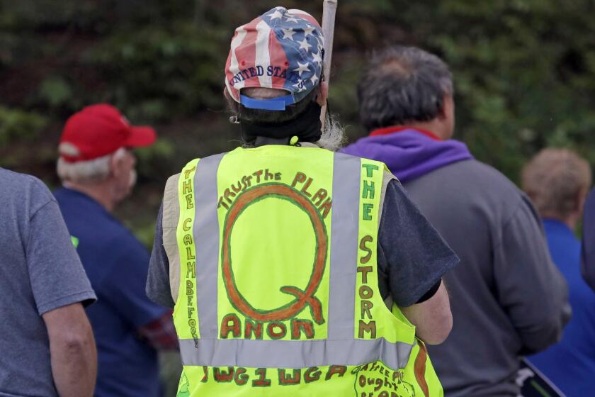 FILE - In this May 14, 2020, file photo, a person wears a vest supporting QAnon at a protest rally in Olympia, Wash., against Gov. Jay Inslee and Washington state stay-at-home orders made in efforts to prevent the spread of the coronavirus. President Joe Biden's inauguration has sown a mixture of anger, confusion and disappointment among believers in the baseless QAnon conspiracy theory. (AP Photo/Ted S. Warren, File)