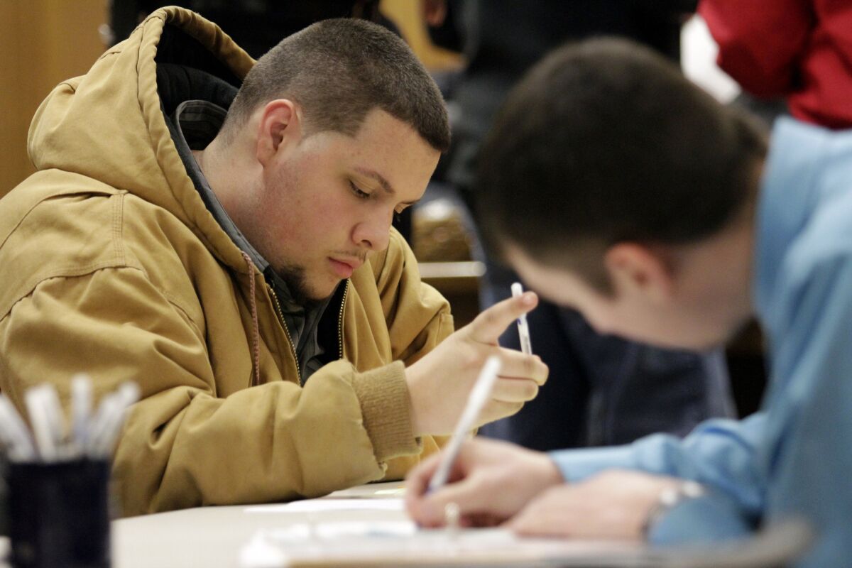 Tyler Kelly, 19, left, fills out applications for parking enforcement and environmental compliance jobs during a public safety job fair at City Hall in Saginaw, Mich., on Jan. 29.