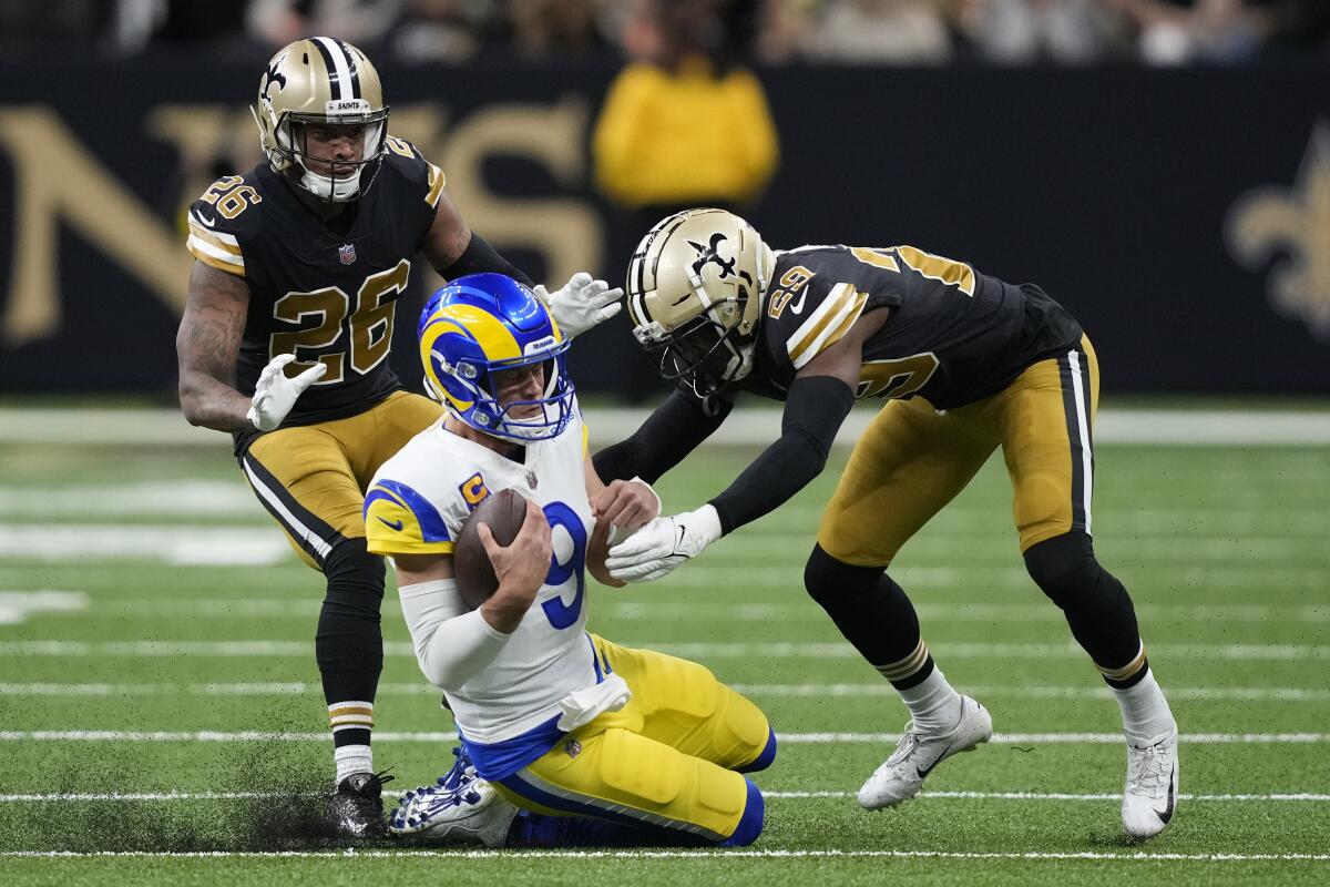 Rams quarterback Matthew Stafford (9) slides near   cornerbacks P.J. Williams (26) and Paulson Adebo (29) in the first half.