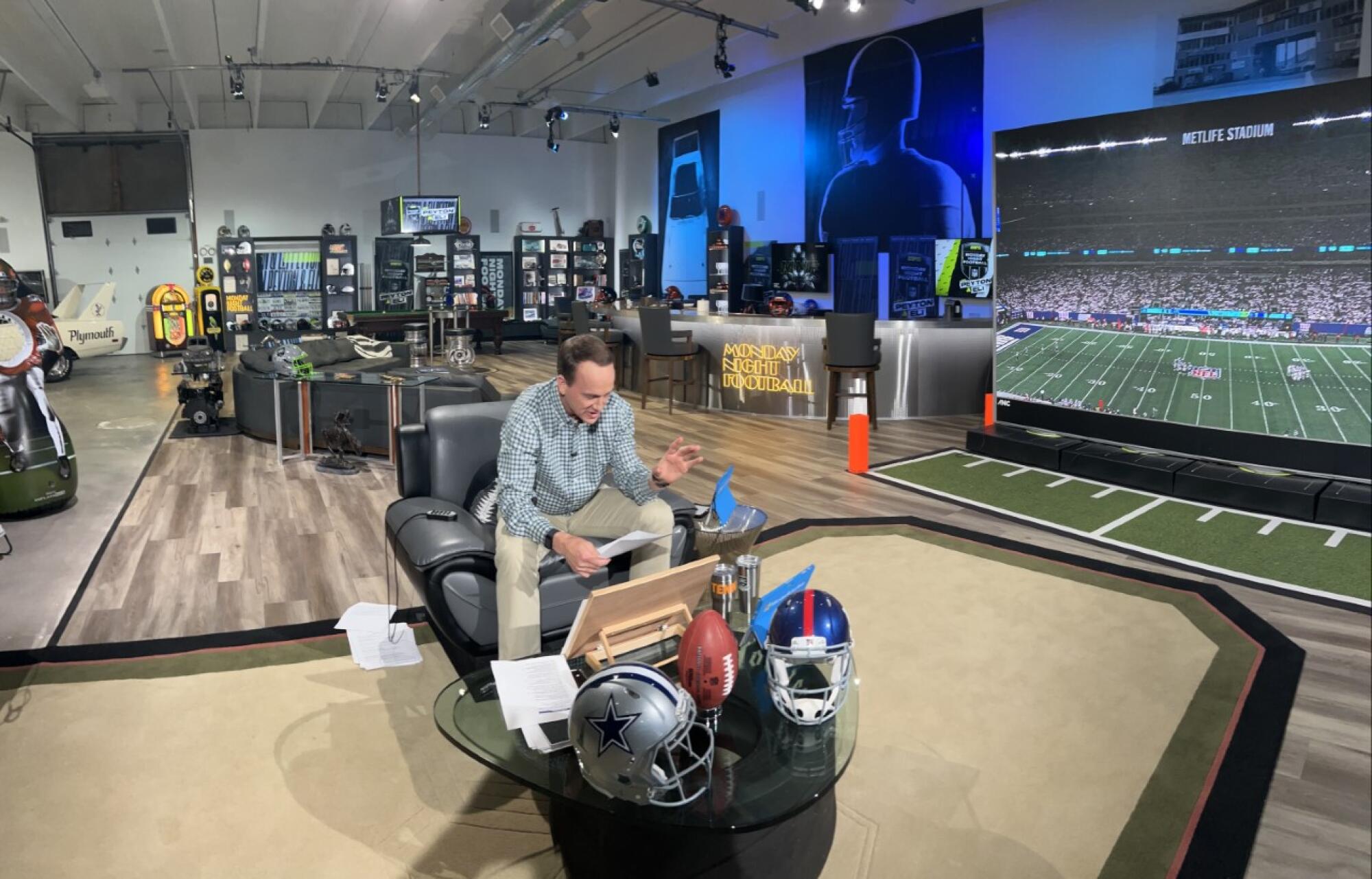 Peyton Manning sits on his set, built inside a vintage car garage in Denver.
