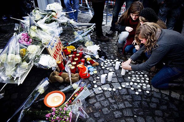 People light candles and place flowers as victims of the tragedy are remembered in Place Saint-Lambert, Liege, Belgium. A wounded child died late Tuesday after the shooting and grenade attack on a Belgian Christmas market, raising the death toll to five, a news report said, including the perpetrator.