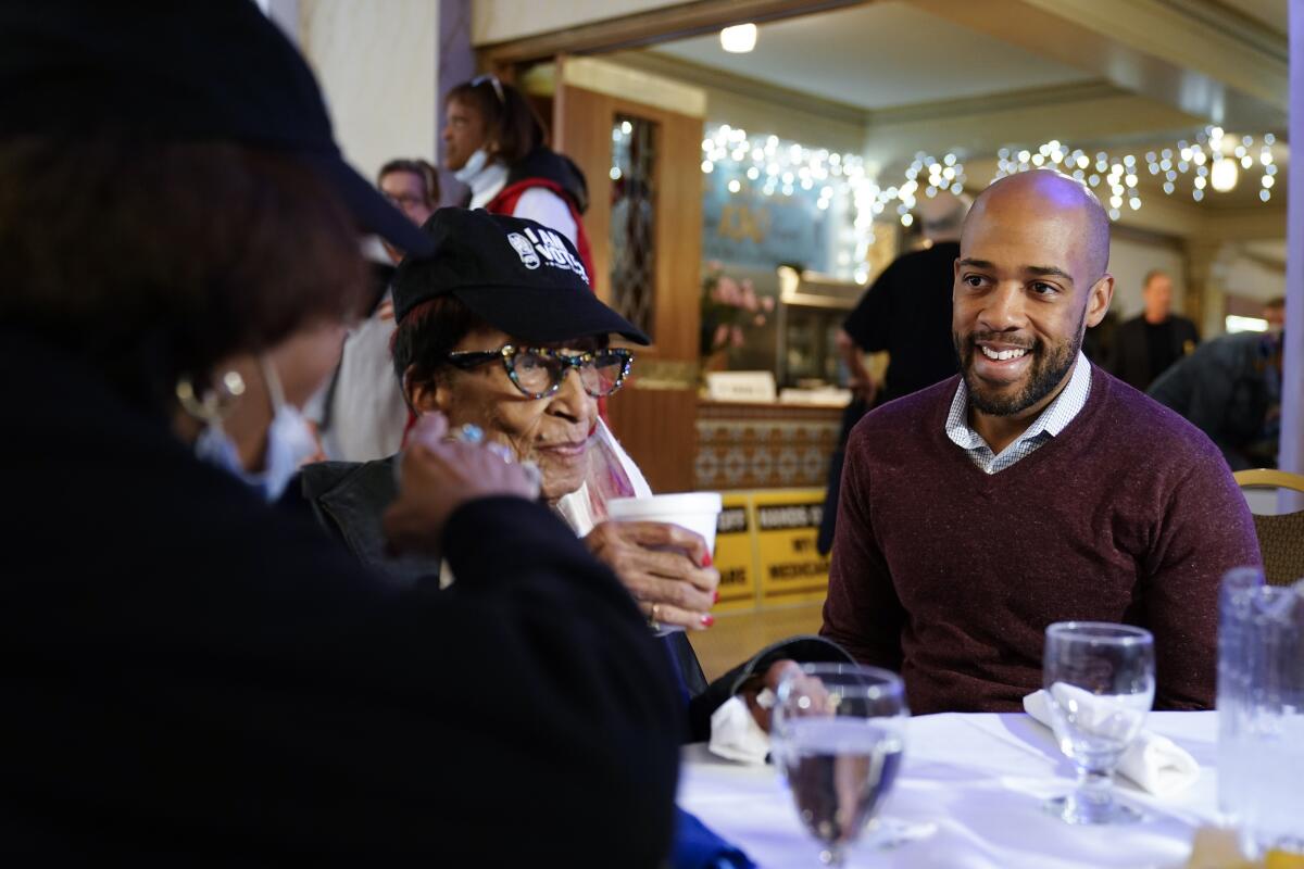 U.S. Senate candidate Mandela Barnes sits at a restaurant table with two voters.