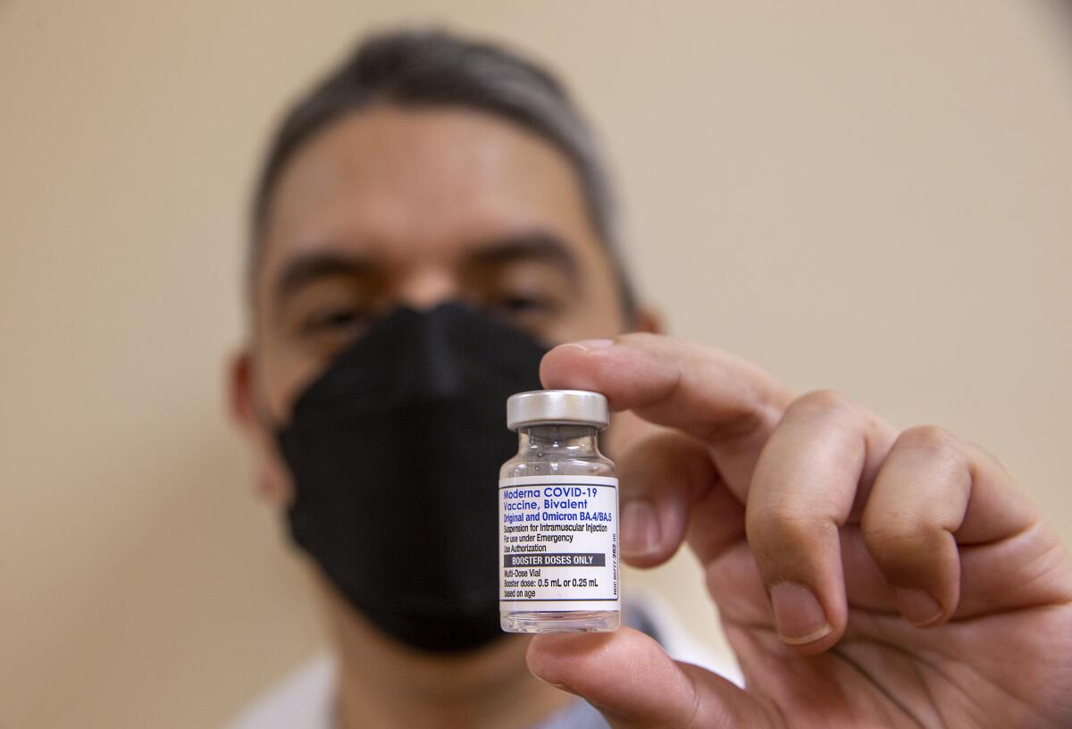 A pharmacist holds a bottle of bivalent COVID-19 vaccine.