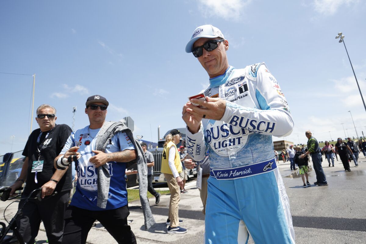 Kevin Harvick, right, signs autographs as he heads to pit road before the start of a NASCAR Cup Series auto race at Kansas Speedway in Kansas City, Kan., Sunday, May 15, 2022. (AP Photo/Colin E. Braley)