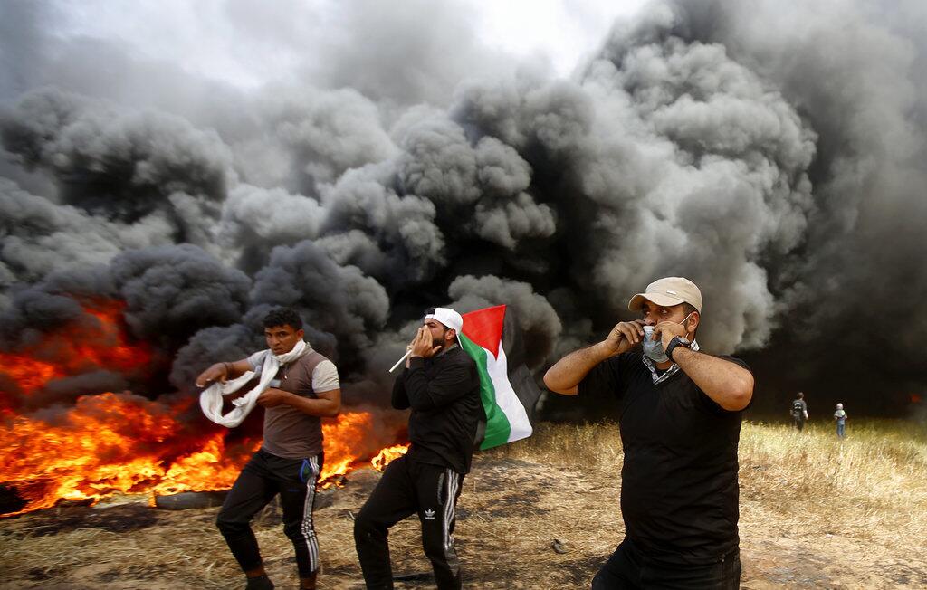 Palestinian protesters chant slogans next to burning tires Friday during clashes with Israeli troops along Gaza's border with Israel, east of Khan Younis, Gaza Strip.