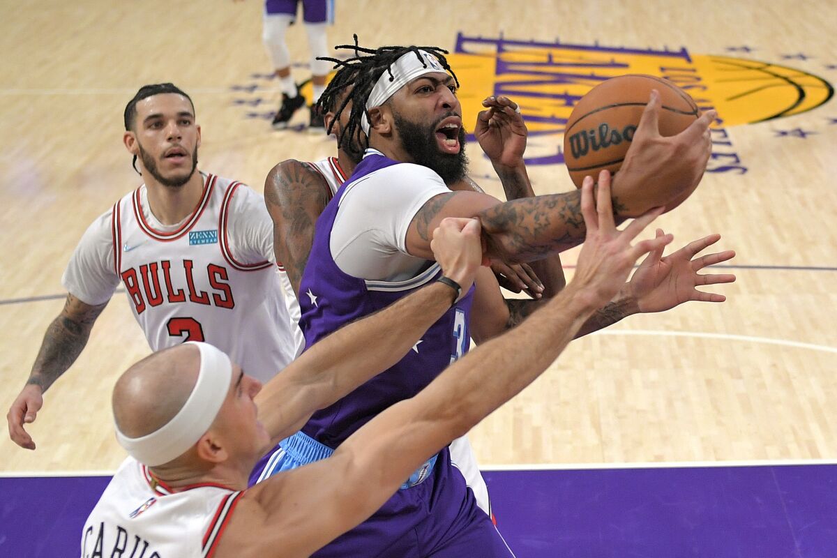 Los Angeles Lakers forward Anthony Davis, right, grabs a rebound away from Chicago Bulls guard Alex Caruso, lower left, and forward Derrick Jones Jr., second from right, as guard Lonzo Ball watches during the first half of an NBA basketball game Monday, Nov. 15, 2021, in Los Angeles. (AP Photo/Mark J. Terrill)