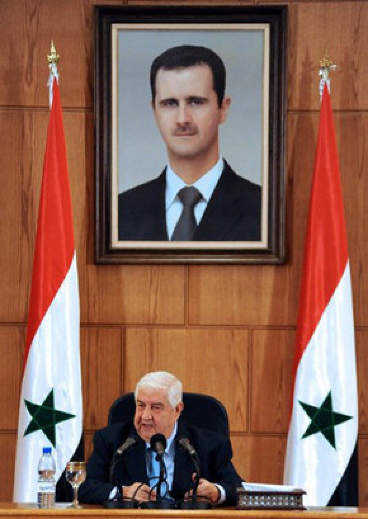 Syrian Foreign Minister Walid Moallem speaks Tuesday under a portrait of President Bashar Assad during a news conference in Damascus.