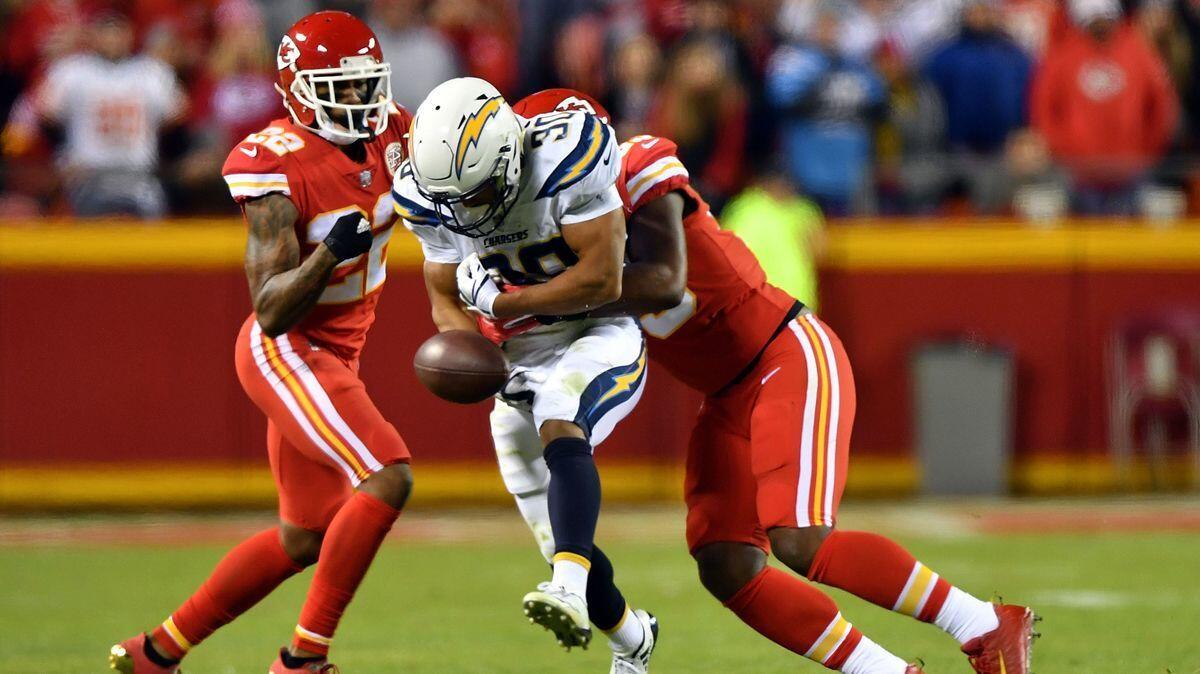 Kansas City Chiefs cornerback Marcus Peters (22) and inside linebacker Reggie Ragland (59) strip the ball from Chargers running back Austin Ekeler on Sunday.