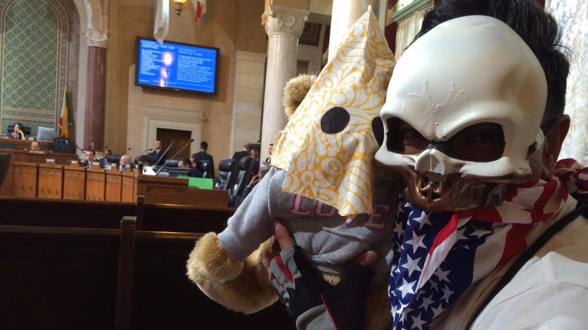Armando Herman attended a City Council committee meeting carrying a stuffed bear dressed in a swastika-decorated hood.