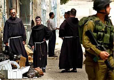 Monks stand in the alley off Manger Square as Israeli soldiers continue their standoff with Palestinians inside the Church of the Nativity.