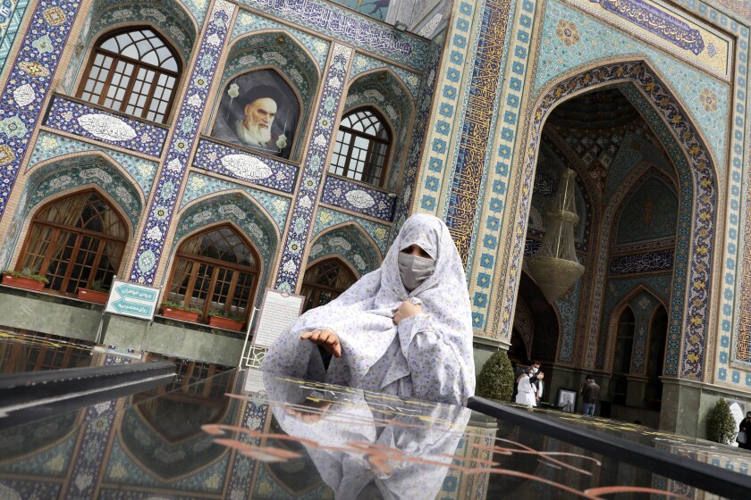 A woman prays at the grave of an unknown soldier who was killed during 1980-88 Iran-Iraq war, at the shrine of Saint Saleh in northern Tehran, Iran, Tuesday, April 6, 2021. .(AP Photo/Vahid Salemi)