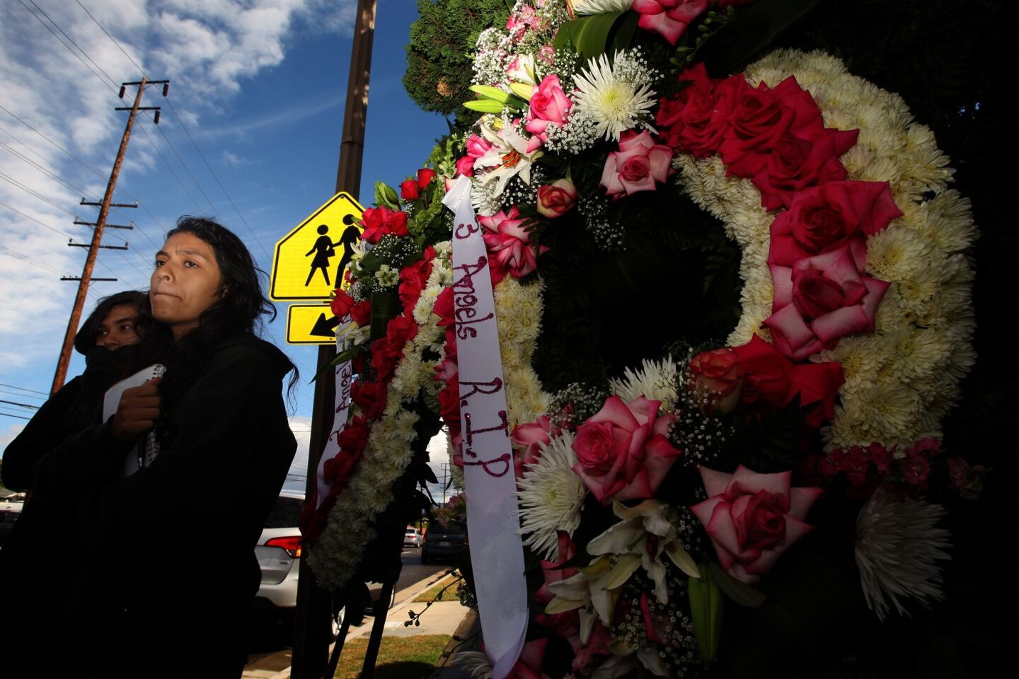 Clarissa Cisneros, 17, who witnessed the accident, stands next to the memorial to the three 13-year-olds killed by a hit-and-run driver near Fairhaven Elementary School on Friday.