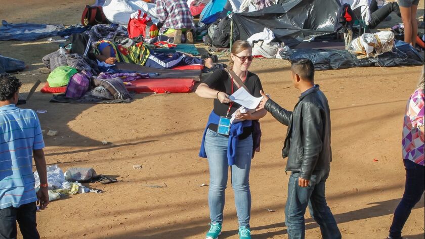 A woman, (who refused to be identified) from a group called El Otro Lado, hands out asylum information to caravan migrants at the temporary shelter called Unidad Deportiva Benito Juarez on Wednesday in Tijuana, Mexico.