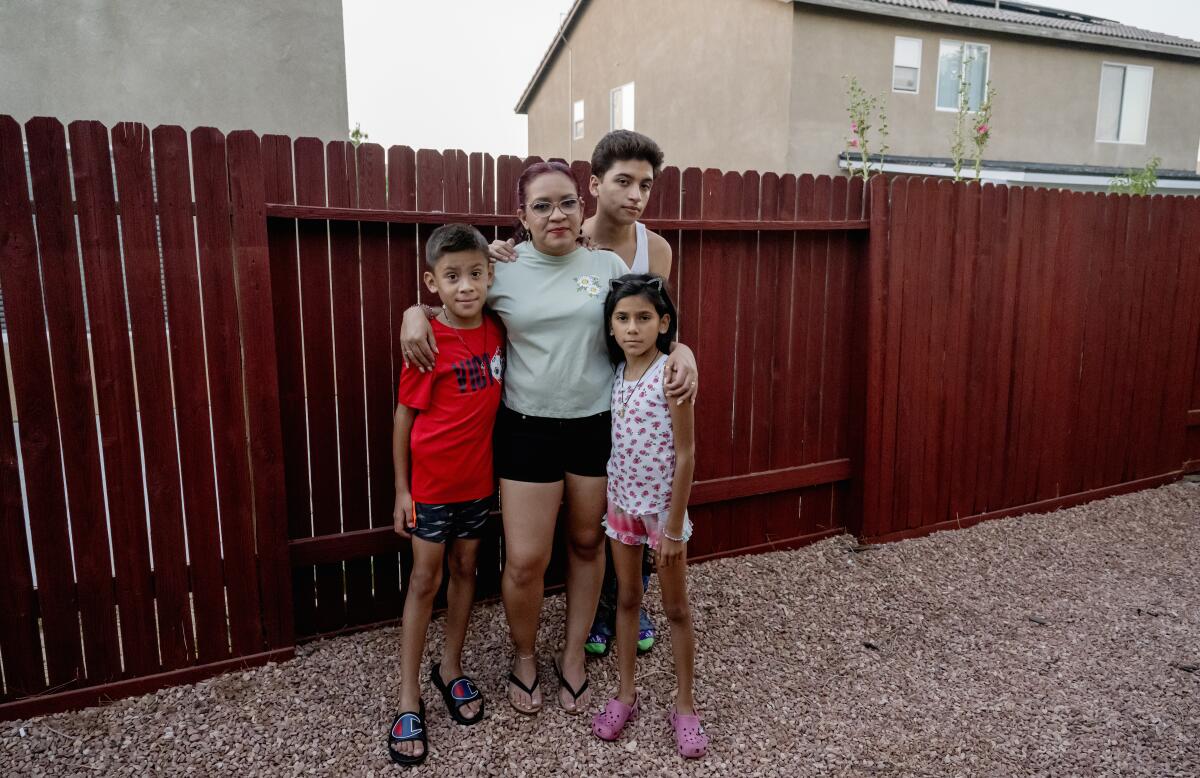 A woman and three children pose before a backyard fence.