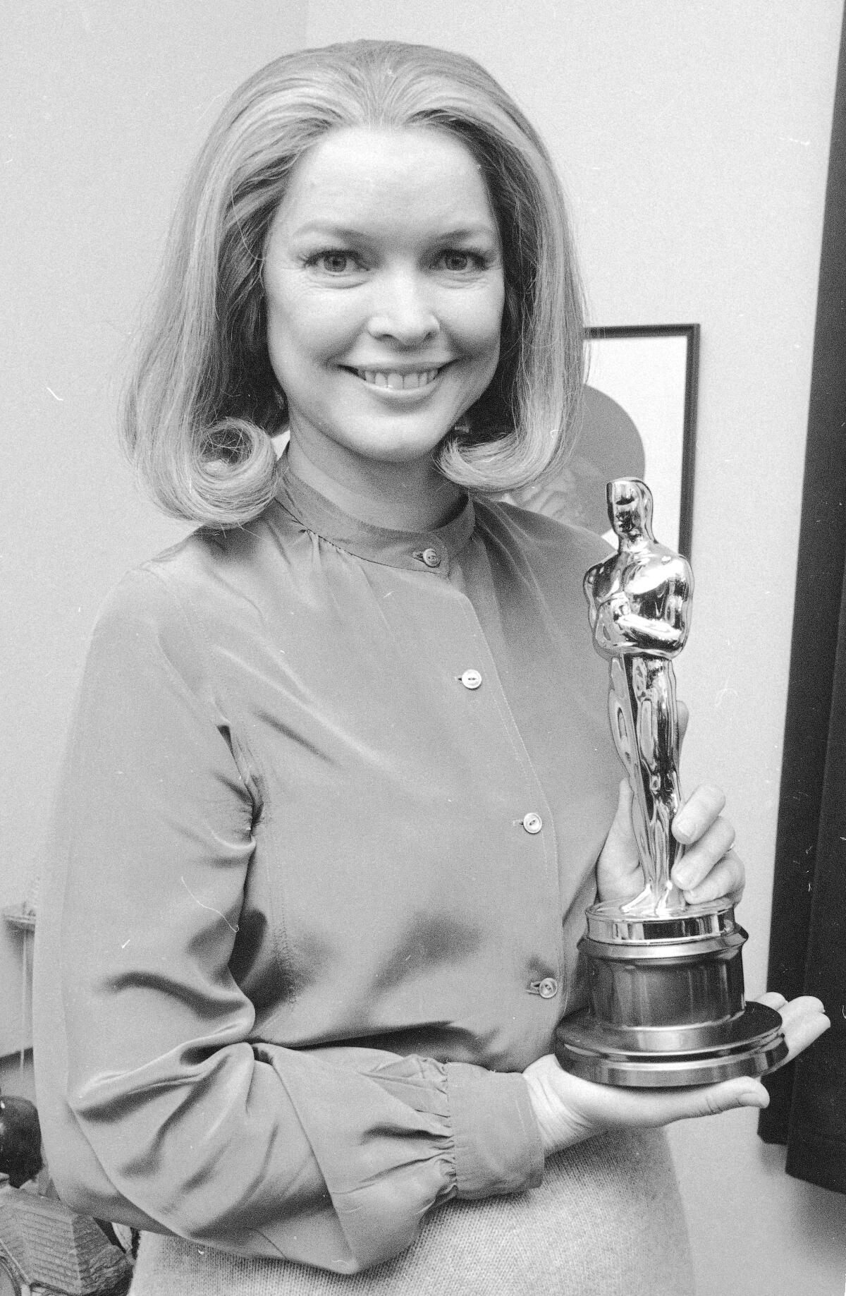 A woman with an Oscar smiles.