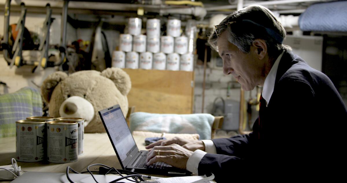 A man in a suit working on a laptop in the documentary “How to Survive a Pandemic.”