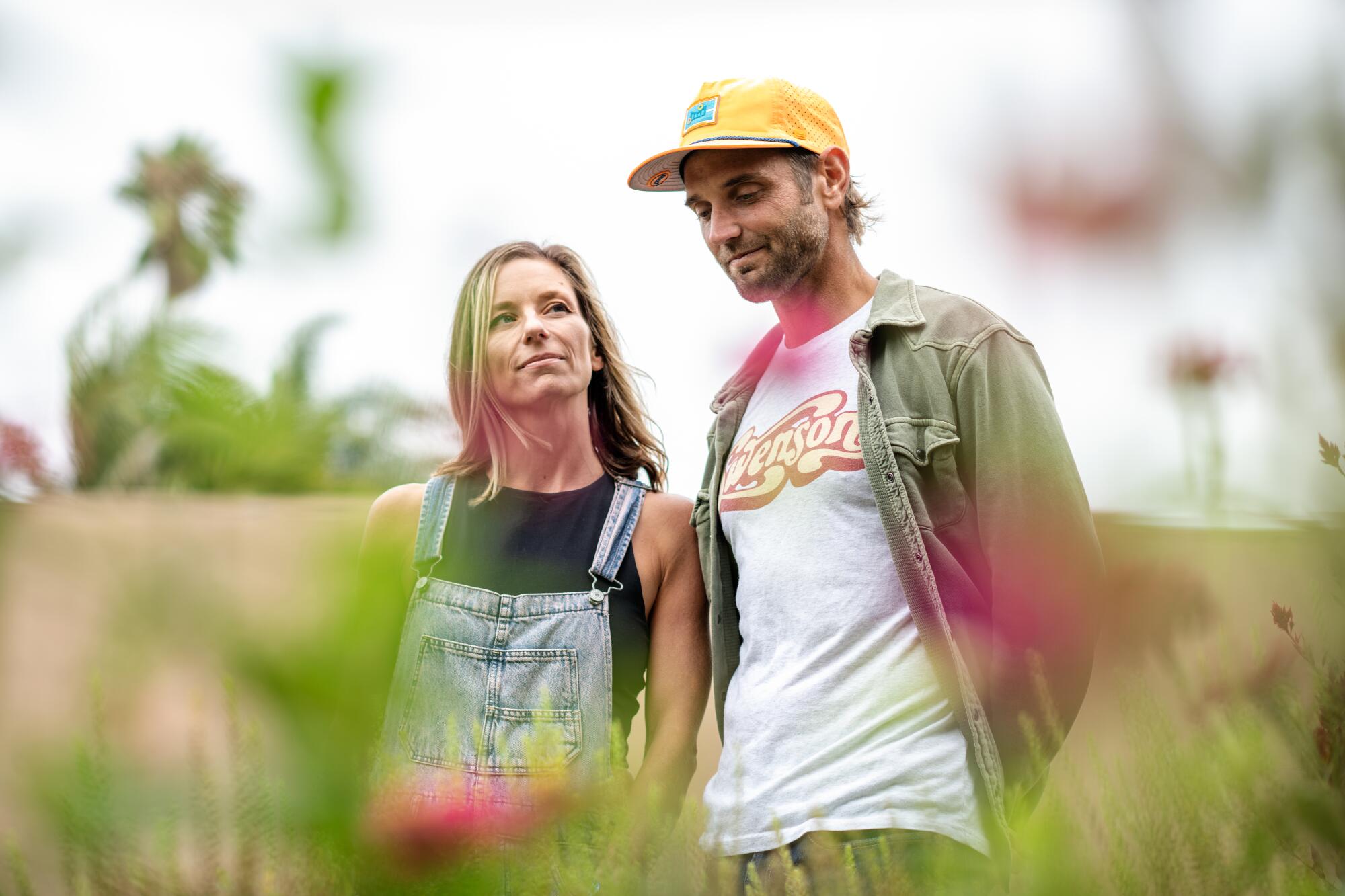 A man and a woman stand in a flower garden.